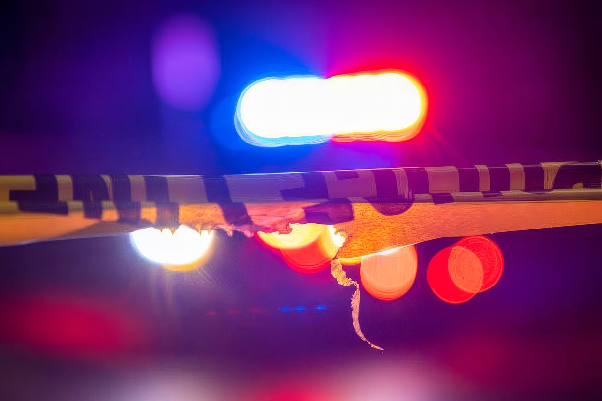 istockphoto-1422110945-612x612-topazStandOther-enhance-2x A defocused police car sits behind crime scene tape with flashing lights at night.